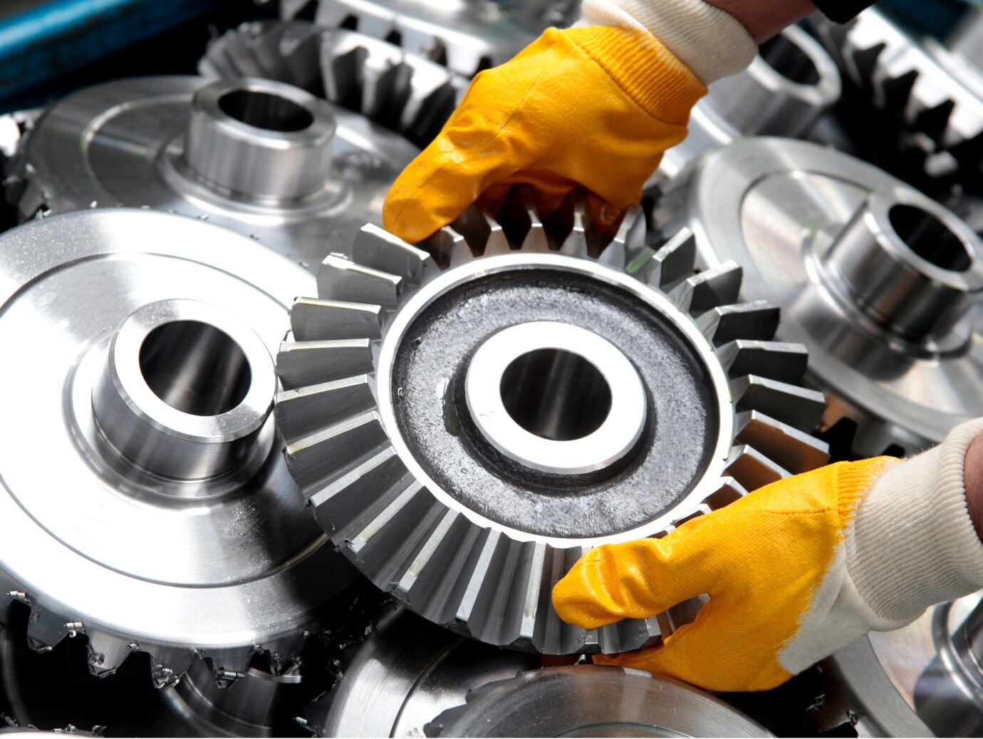 Two hands lifting a gear from the pile of gears.