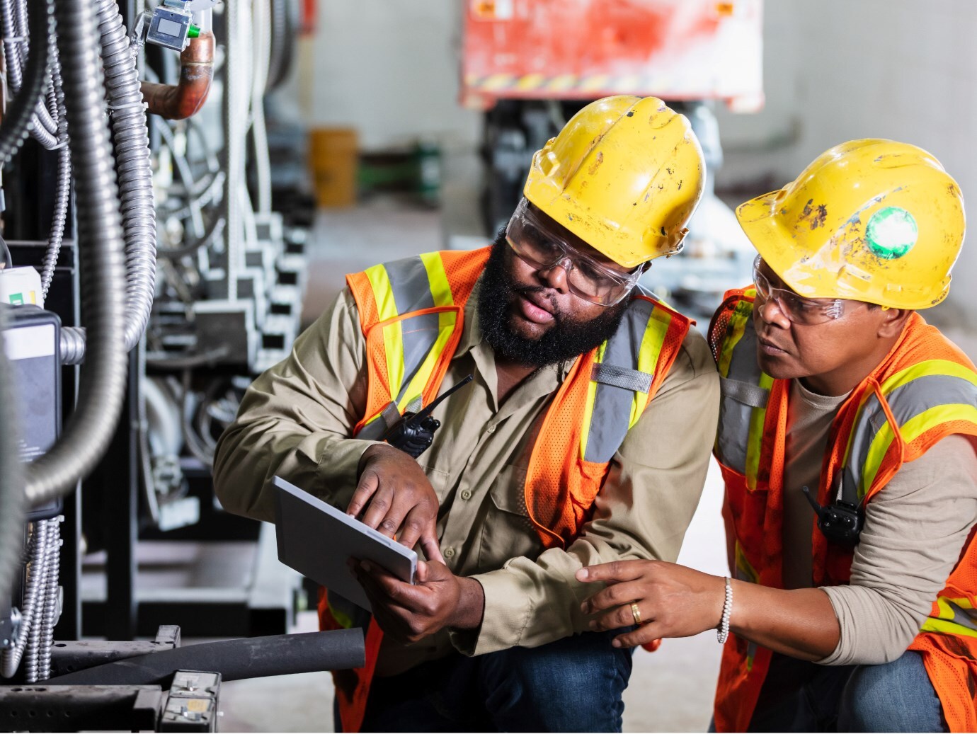 Two employees with protective gears looking into the tablet in the factory
