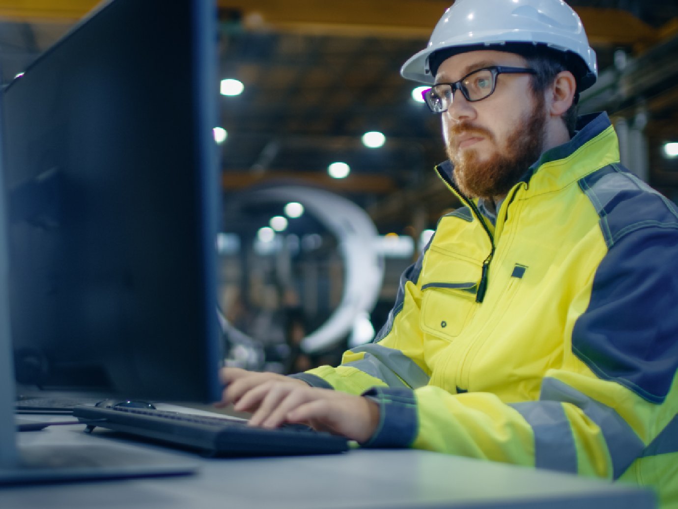 A factory worker in a uniforms working on the laptop